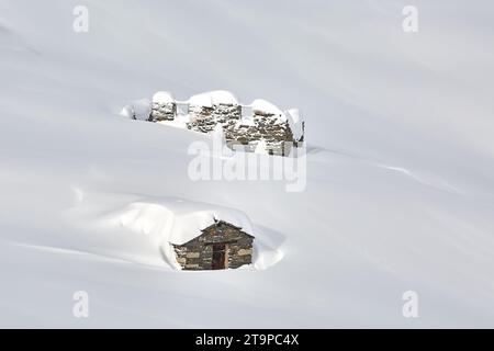 Ruined buildings in deep snow, high mountains Stock Photo