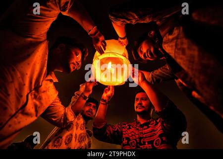 Varanasi, India. 26th Nov, 2023. A group of young people light a Sky Lantern during the Dev Deepavali Festival at Varanasi. Dev Deepavali/Diwali is the biggest festival of light celebration in Kartik Poornima (Mid-Autumn) where devotees decorate the river bank with millions of lamps during the festival. (Photo by Avishek Das/SOPA Images/Sipa USA) Credit: Sipa USA/Alamy Live News Stock Photo