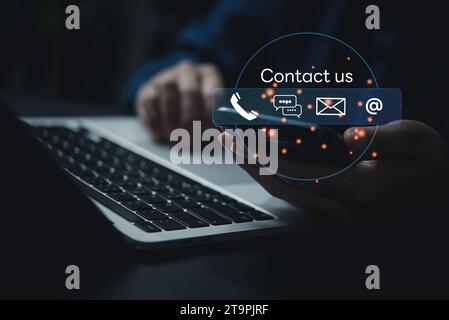 Technology communication Contact us or Customer support hotline service and online network. Businessman using mobile chat and laptop on virtual screen Stock Photo