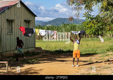 El Seibo, Dominican Republic. 21st Nov, 2023. A man grabs clothes off a clothesline in a batey, or community, in El Seibo, Dominican Republic on Nov. 21, 2023. Most residents of these communities are either undocumented Haitian immigrants or denationalized Dominicans of Haitian descent. The United States blocked the Central Romana Corporation, Ltd. from importing sugar into the country on Nov. 23, 2022 after allegations of forced labor were levied against the company. (Photo by Carlos Berríos Polanco/Sipa USA) Credit: Sipa USA/Alamy Live News Stock Photo