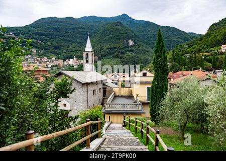 Lush mountainous landscape can be seen beyond Chiesa di Sant Antonio Abate di Vezio, an ancient Italian medieval church in Perledo, Lombardy, Italy. Stock Photo