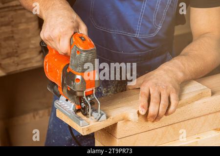 A carpenter using a jigsaw to cut wood cuts bars. Stock Photo