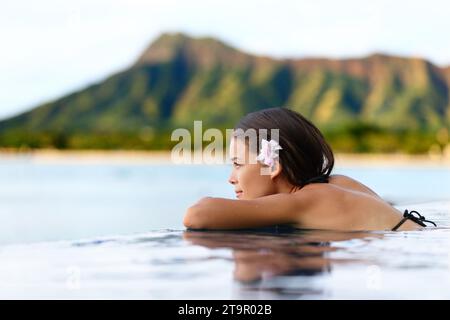 Infinity pool resort woman relaxing at sunset overlooking Waikiki beach in Honolulu city, Oahu island, Hawaii, USA. Wellness and relaxation concept fo Stock Photo