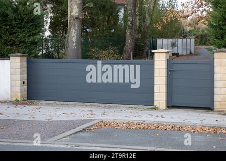 portal facade aluminum sliding grey metal gate and pedestrian door access of modern gray suburb house entrance Stock Photo