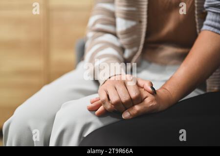 Close up of grown up daughter holding hands of old mother for giving support, empathy and understanding Stock Photo