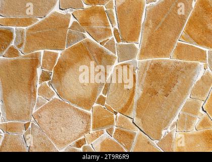 Beige and yellow rustic mosaic nature stone wall from small parts. Vintage decorative elements. Abstract geometric pattern or background for design Stock Photo