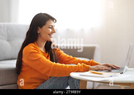 Side view of happy indian lady typing on laptop keyboard Stock Photo
