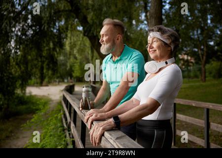 Happy elderly woman and man friends having nice conversation resting after run Stock Photo