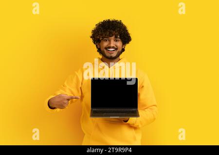 Cool young indian guy showing laptop with black screen Stock Photo