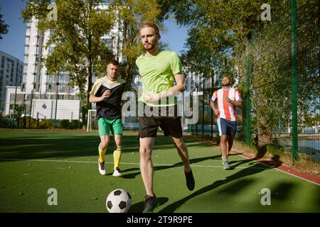 Sportsmen team playing football on field at countryside Stock Photo