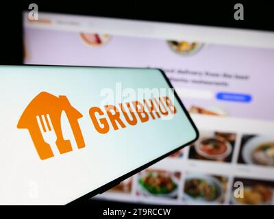 Mobile phone with logo of American food ordering and delivery company Grubhub Inc. in front of website. Focus on center-left of phone display. Stock Photo