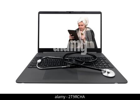 Laptop and medical stethoscope isolated on white background. On laptop screen - a girl is holding a blister with pills and a tablet PC in her hands Stock Photo