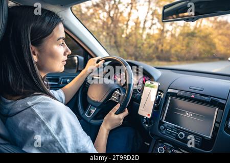 Woman using navigation app on smartphone while driving a car. Stock Photo