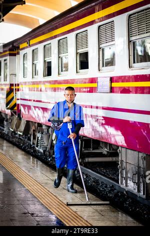 A Thai cleaner makes his way along the platform mopping and sweeping the dirt and dust in Hua Lamphong Train station, Bangkok, Thailand. Stock Photo