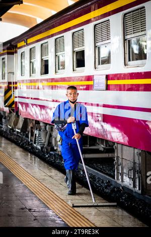 A Thai cleaner makes his way along the platform mopping and sweeping the dirt and dust in Hua Lamphong Train station, Bangkok, Thailand. Stock Photo