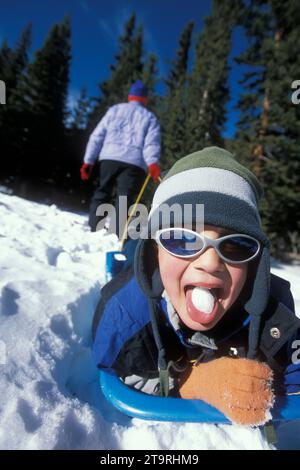 Estes Park, Colorado. A child is pulled by his mother on a sled. Stock Photo