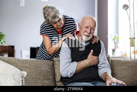 Senior man suffering from chest pain while his wife comforting him Stock Photo