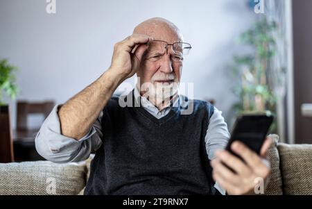 Senior man staring at his smartphone in confusion Stock Photo