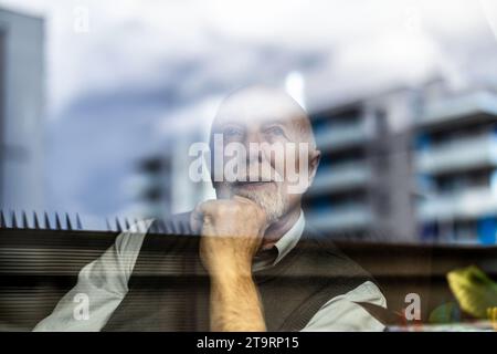 Portrait of thoughtful senior man looking through window Stock Photo