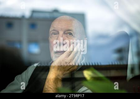 Portrait of thoughtful senior man looking through window Stock Photo