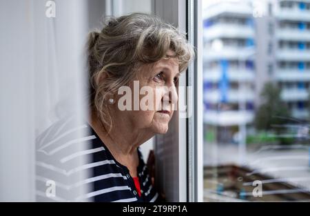 Portrait of senior woman looking through window Stock Photo
