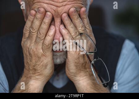 Depressed Senior Man Covered His Face With Both Hands Stock Photo
