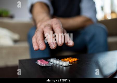 Close-up of man taking pills on sofa at home in the living room Stock Photo