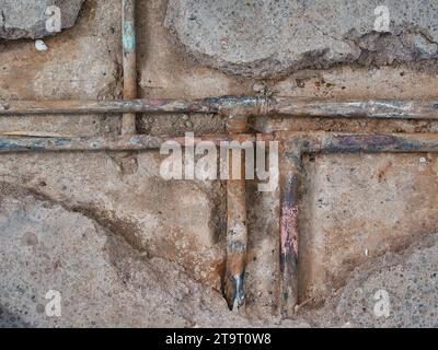 Exposed, leaking copper central heating pipes, badly corroded after being buried in the concrete floor slab of a house of around 60 years. Stock Photo