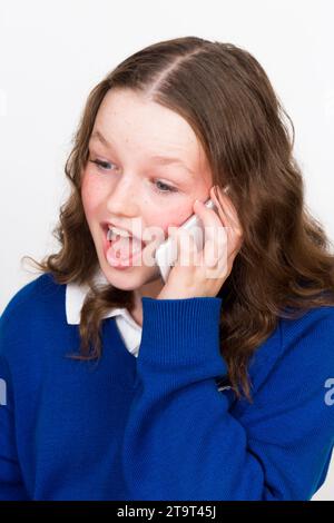 Year 7 school girl child aged 11 years / year old kid wearing school uniform & apple iphone mobile smart telephone device to make phone call. UK. (136) Stock Photo
