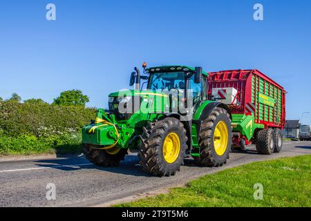 John Deere 6215R Farm Tractor & Strautmann Giga-Vitesse 3602 Forage Wagon.  Farm machinery travelling on public roads in Cheshire UK Stock Photo