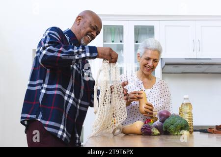 Happy diverse senior couple unpacking groceries in kitchen. Lifestyle, retirement, senior lifestyle, shopping, togetherness and domestic life, unalter Stock Photo