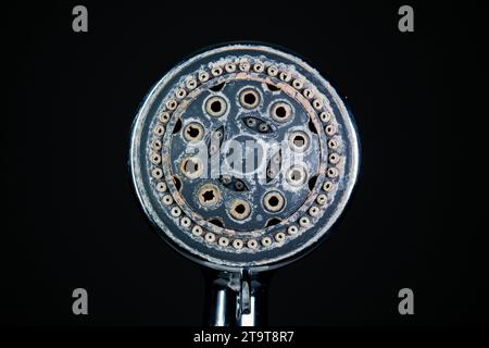 Hard water calcium or lime scale deposits on old, worn out shower head. Close up studio shot, isolated on black, no people. Stock Photo