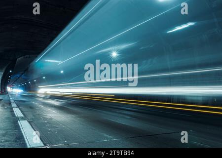Trails of car lights passing fast through the highway tunnel in perspective. Stock Photo