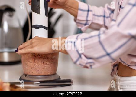 woman using blender and grinding meat. Preparation of minced meat. Stock Photo