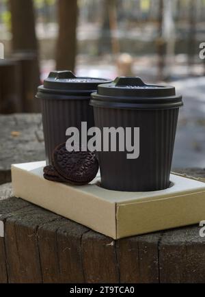 Two paper coffee cups on a paper tray, with biscuits on the side, wooden stump. Stock Photo