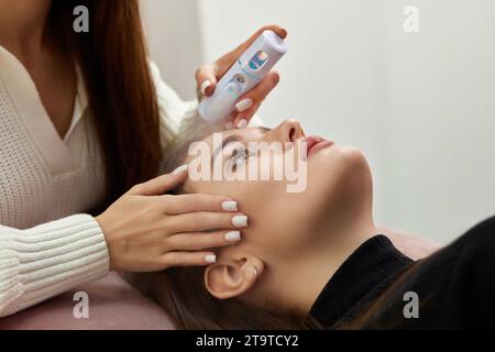 cosmetologist using primer spray for eyelash extension procedure in salon Stock Photo