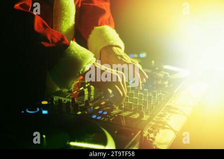 Santa Claus DJ mixing music on a Christmas party in bright stage lights. Stock Photo
