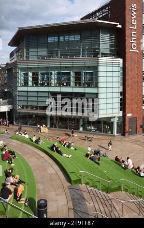 Shoppers Siiting on Artificial Turf Terraces in the Liverpool One City Centre Shopping Centre & the Modern John Lewis Building Liverpool England UK Stock Photo