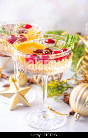 Christmas champagne fruit punch with cranberry, orange, spices and rosemary. Sweet alcohol cocktail glasses, on Christmas and New Year decorated backg Stock Photo