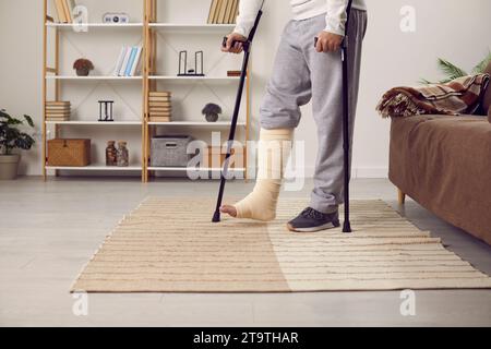 Handicapped young man with broken leg trying to walk with crutches. Stock Photo