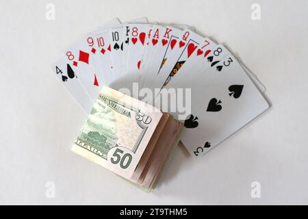 A wad of dollar notes with some playing cards Stock Photo