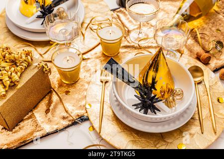 New Years Eve celebration. Holidays served table with champagne and and luxury golden cutlery, with decoration and Christmas decor Stock Photo