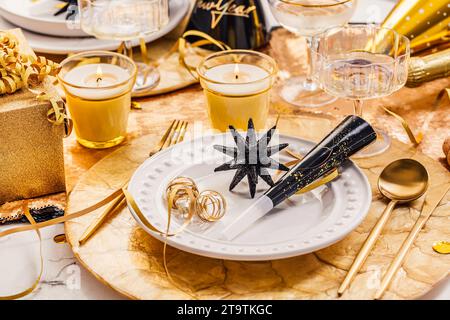New Years Eve celebration. Holidays served table with champagne and and luxury golden cutlery, with decoration and Christmas decor Stock Photo