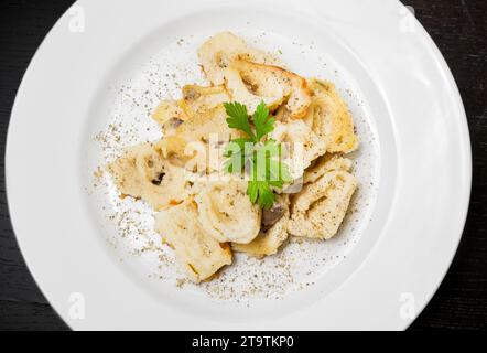 top of view of dish of italian swivels pasta with porcini mushrooms and sauce bechamel with pepper on old black table Stock Photo