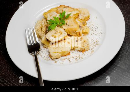 top of view of dish of italian swivels pasta with porcini mushrooms and sauce bechamel with pepper near fork on black table; top of view of dish of italian swivels pasta with porcini mushrooms and sauce bechamel with pepper near fork on black table Stock Photo