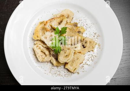 top of view of dish of italian swivels pasta with porcini mushrooms and sauce bechamel with pepper on old black table Stock Photo