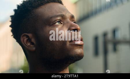 Moving shot close up inspired contemplating biracial guy pensive thinking man looking around on urban city building skyscrapers think look up in sky Stock Photo