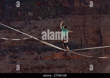 Telephoto view of a man walking a highline at the GGBY World Highline Festival in Mineral Canyon near Moab, Utah. Stock Photo