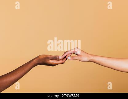 Close up of two female hands together on brown background. Hands of two african american women. Stock Photo