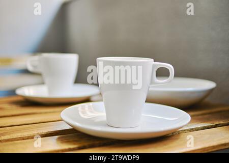 Two white tea cups on table in terraced area, no people Stock Photo